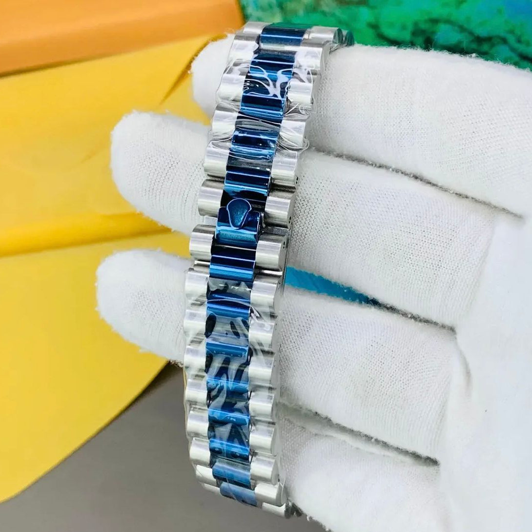 Silver and blue bracelet on a white gloved hand with colorful background